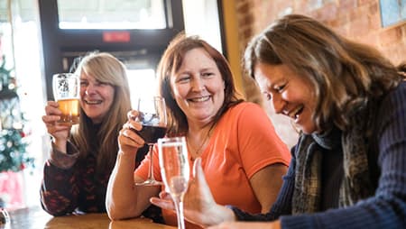 Three adult women socializing with wine