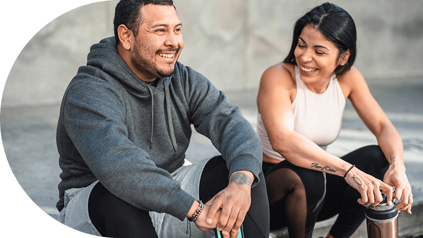 Two adults sitting on a curb after a workout