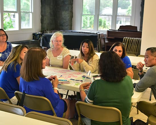 Adults in a meeting sitting around a table