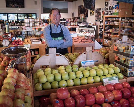 Grocery store clerk standing behind a stand of apples
