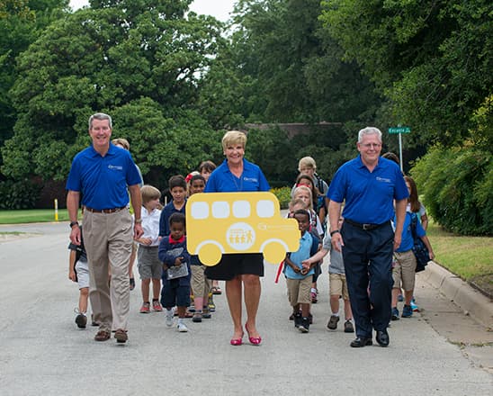 Three school administrators leading a group of young students